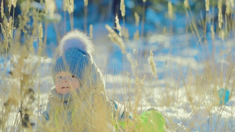 Glückliches-Baby-im-Schnee-liegen-und-lachen.-Schaut-sich-um.-Wintertag.-Close-up