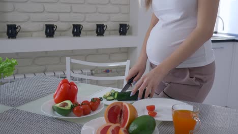 nutrition-of-pregnant-women,-expectant-female-with-big-stomach-is-cooking-useful-meal-for-healthy-tasty-brunch-from-fresh-vegetables