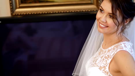 Close-up,-Braut-Gebühren.-die-Braut-ist-für-die-Hochzeit-gekleidet.-Porträt-einer-lächelnden,-schönen-Braut-in-Schleier-und-Spitze-Kleid.-Brautjungfer-Schnürsenkel-bis-weißer-Spitze-Kleid-mit-Schleife.-Details-der-Hochzeit-Kleid