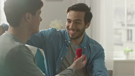Gay-Marriage-Proposal-Concept.-Adorable-Boyfriend-Gifts-a-Beautiful-Shiny-Wedding-Ring-to-His-Cute-Hispanic-Fiance.-Surprised-Partner-is-Extremelly-Happy-and-Hugs-His-Queer-Friend.-Relationship-Goals.