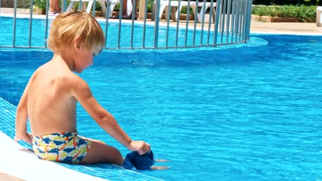 Happy-little-boy-sitting-near-the-pool