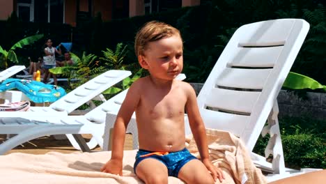 Happy-little-boy-sitting-near-the-pool