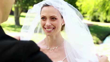 Groom-lifting-veil-off-beaming-brides-face