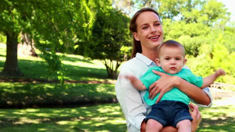 Feliz-madre-sosteniendo-Monada-bebé-niño-sonriendo-a-la-cámara