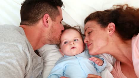 Baby-boy-in-blue-babygro-with-happy-parents-on-bed