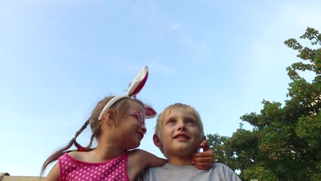 Niña-con-orejas-y-gafas-y-boy-con-la-diversión-de-pelo-blanco-que-habla-en-el-fondo-de-cielo-azul.