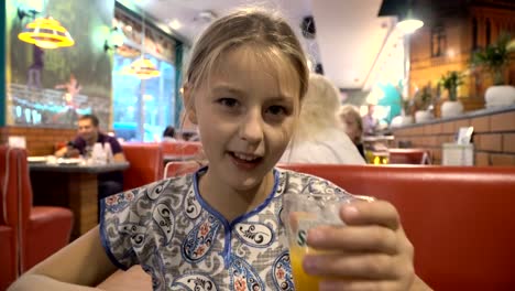 La-niña-está-bebiendo-jugo-en-un-café.