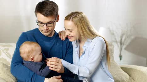 Familia-feliz.-El-padre-amorosamente-sostiene-a-su-pequeño-bebé-y-luego-se-lo-da-a-su-esposa.