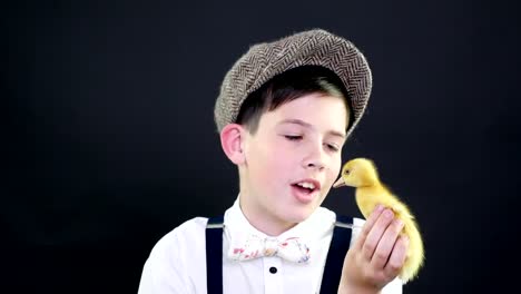 Retrato,-un-chico-guapo-en-una-gorra-y-ligas-se-juega-con-un-pequeño-patito-amarillo.-Video-con-decoración-temática-de-estudio