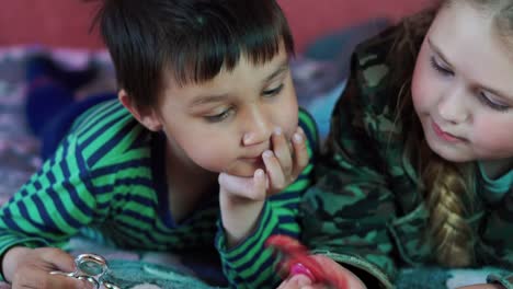 multi-ethnic-Little-boy-and-girl-playing-with-the-spinner-lying-on-the-couch-4K