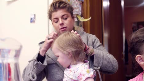 Young-woman-is-combing-girl's-hair