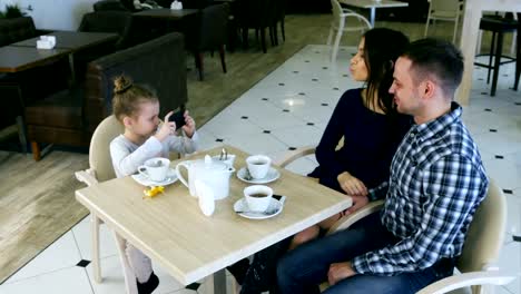 Moderne-Mädchen-macht-Fotos-von-schönen-Eltern-im-café