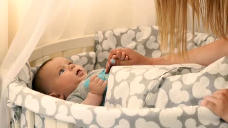 Young-mother-raise-up-her-baby-by-the-hands-in-the-crib