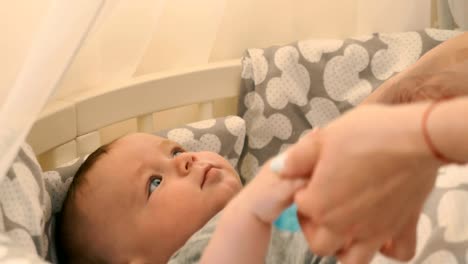 Mother-takes-a-little-son-by-hands-to-put-him-in-the-crib