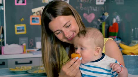 Joven-madre-alimenta-a-su-pequeño-hijo-con-un-albaricoque