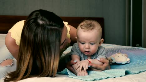 Retrato-de-niño-lindo-bebé-con-la-madre-sonriente-joven-en-la-cama