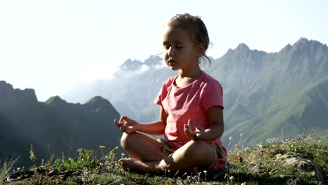 Little-cute-girl-meditating-on-top-of-mountain