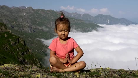 Little-cute-girl-meditating-on-top-of-mountain