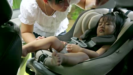 joven-madre-asiática-hermosa-desabrochar-a-su-hija-desde-su-asiento-de-coche