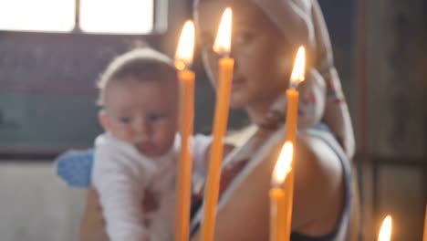 Portrait-of-young-mother-with-little-son-in-front-of-candles-in-church