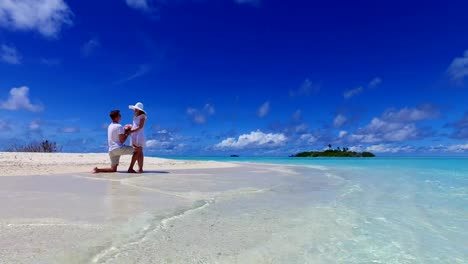 v07384-Maldives-white-sandy-beach-2-people-young-couple-man-woman-proposal-engagement-wedding-marriage-on-sunny-tropical-paradise-island-with-aqua-blue-sky-sea-water-ocean-4k