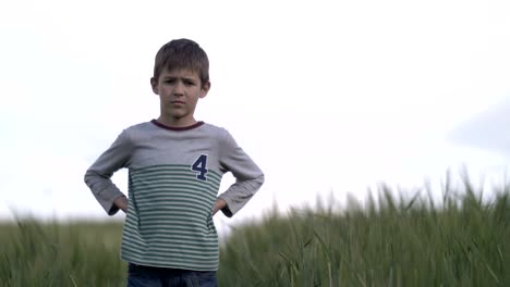 serious-boy-footballer-standing-in-the-wheat-field-looking-at-the-camera