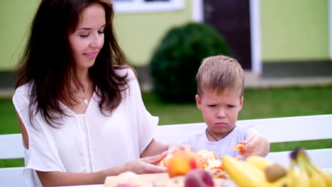 summer,-in-the-garden.-Mom-and-four-year-old-son-cleaned-from-peel-oranges.-they-want-to-make-fresh-juice