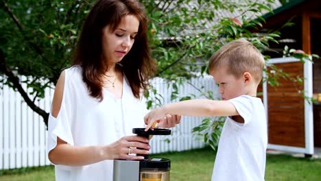 Sommer-im-Garten.-Mutter-und-vier-Jahre-alten-Sohn-machen-frischen-Saft-der-Mandarinen,-legen-Sie-Mandarin-Scheiben-in-einen-Entsafter