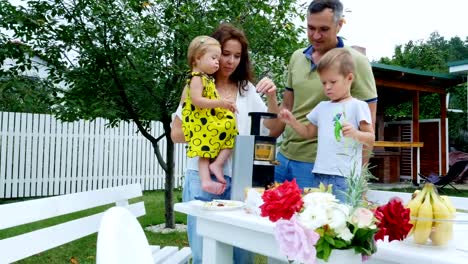 glückliche-schöne-Familie,-Mama,-Papa,-vier-Jahre-alten-Sohn-und-ein-Jahr-alte-Tochter-machen-frischen-Saft-aus-Trauben.-Im-Sommer,-im-Garten.-die-Familie-verbringt-ihre-Freizeit-zusammen