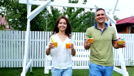 Sommer-in-den-Garten,-Eltern,-Mama-und-Papa,-Carry,-frisch-gepresster-Fruchtsaft,-ihre-Kinder-zu-behandeln.-Die-Familie-verbringt-ihre-Freizeit-zusammen