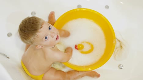 Adorable-niño-salpica-agua-en-la-cuenca-en-el-baño