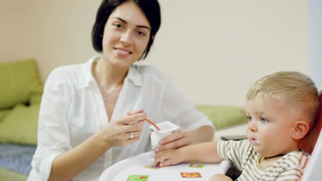 Joven-madre,-alimentan-a-un-pequeño-hijo-con-yogur