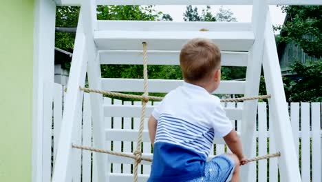 summer,-in-the-garden,-child,-a-four-year-old-boy-climbs-the-children's-stairs-on-the-playground.-The-family-spends-their-leisure-time-together