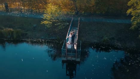 Pareja-joven-está-de-pie-sobre-un-pequeño-puente-cerca-del-lago-hermoso