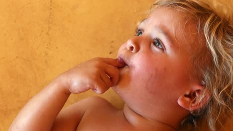 Tiro-vertical-de-niño-infantil-que-se-establecen-en-el-suelo-con-los-dedos-y-la-mano-en-la-boca-pensando-en-algo.-Bebé-infantil-niño-contemplando-sobre-la-vida