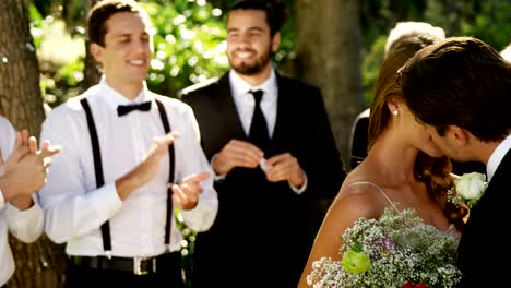 Bride-and-groom-kissing-each-other-and-guests-clapping-In-background-4K-4k