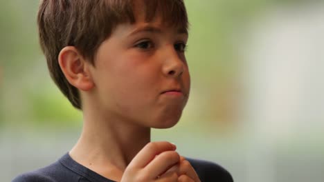 Expressive-boy-doing-grimaces-and-caricatures-with-face-as-he-eats-caloric-cookie.-Bashful-child-doing-funny-faces-to-camera