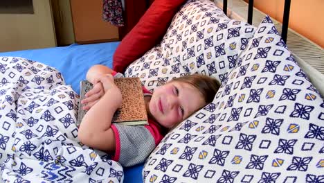 Little-girl-in-bed.-Girl-tryies-get-asleep-with-an-old-father-diary.-Small-girl-with-an-old-book-in-bed.-Family-concept