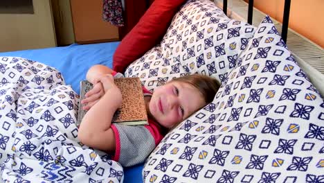 Kleines-Mädchen-im-Bett.-Mädchen-Tryies-bekommen-mit-ein-altes-Tagebuch-Vater-schlief.-Kleines-Mädchen-mit-einem-alten-Buch-im-Bett.-Familienkonzept