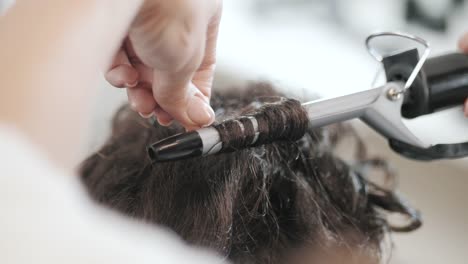 Eine-Frau-in-einem-Friseursalon.-Master-verdrehen-locken-auf-kurzen-Haarschnitt.-Nur-die-Hände.-Slow-motion