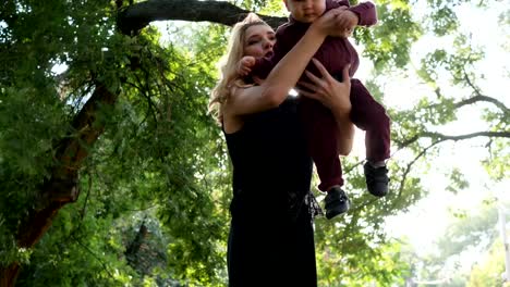 madre-con-bebé-divertirse-tiempo-en-los-árboles-de-fondo-verde-en-el-parque,-feliz-descanso-familiar