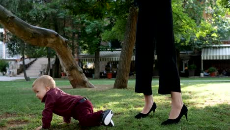 child-is-crawling-on-green-lawn-near-parent-in-slow-motion-on-family-rest