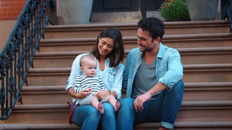 Young-couple-with-a-baby-sitting-on-front-stoop,-close-up