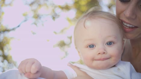 Portrait-of-mother-holding-her-baby-boy-outdoors