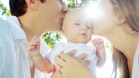 Portrait-of-Caucasian-parents-kissing-child-in-park