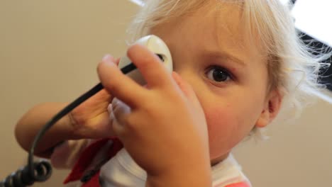 Baby-holding-telephone-to-the-ear.-Toddler-holds-phone-next-to-ear-listening-to-someone-on-the-other-line-in-4K