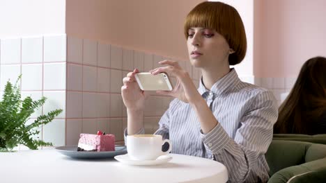Young-beautiful-red-haired-girl-doing-photo-of-cake-while-sitting-in-cafe.-Problem-today,-social-network.-60-fps