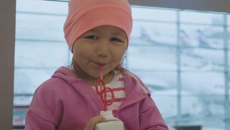 Retrato-de-un-niño-beber-jugo-y-mirando-a-la-cámara-en-el-aeropuerto