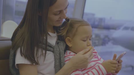 Mother-feeds-her-little-daughter-with-tangerine-at-airport-in-slow-motion