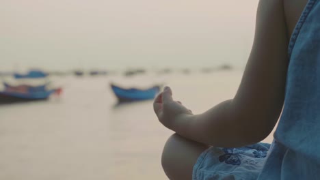 Kleine-süße-Mädchen-meditiert-in-türkischen-Pose-am-Meer